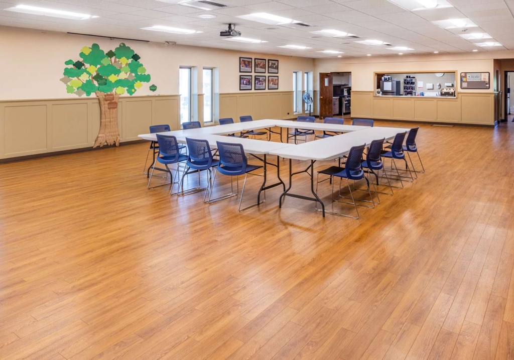 Interior photo of the community room of First Congregational Church of Naperville. The room has a large floor area, kitchen, and plenty of room for tables and chairs.
