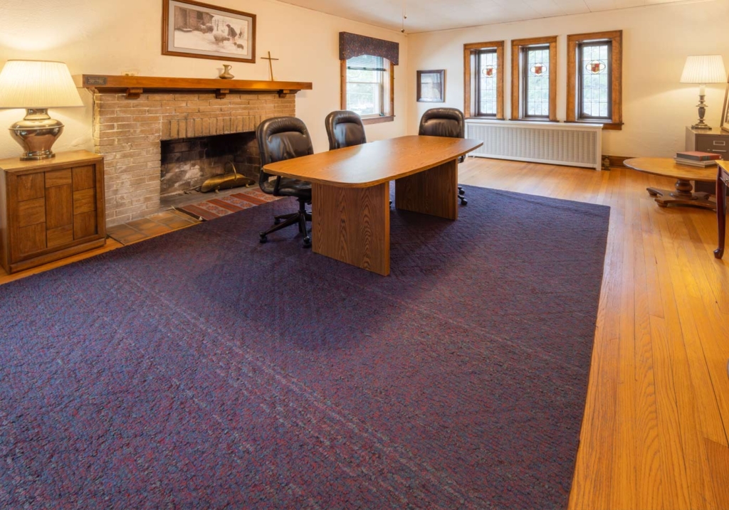 The interior of the Fireside room within First Congregational UCC Naperville. A cozy room with a fireplace, rug, and table.