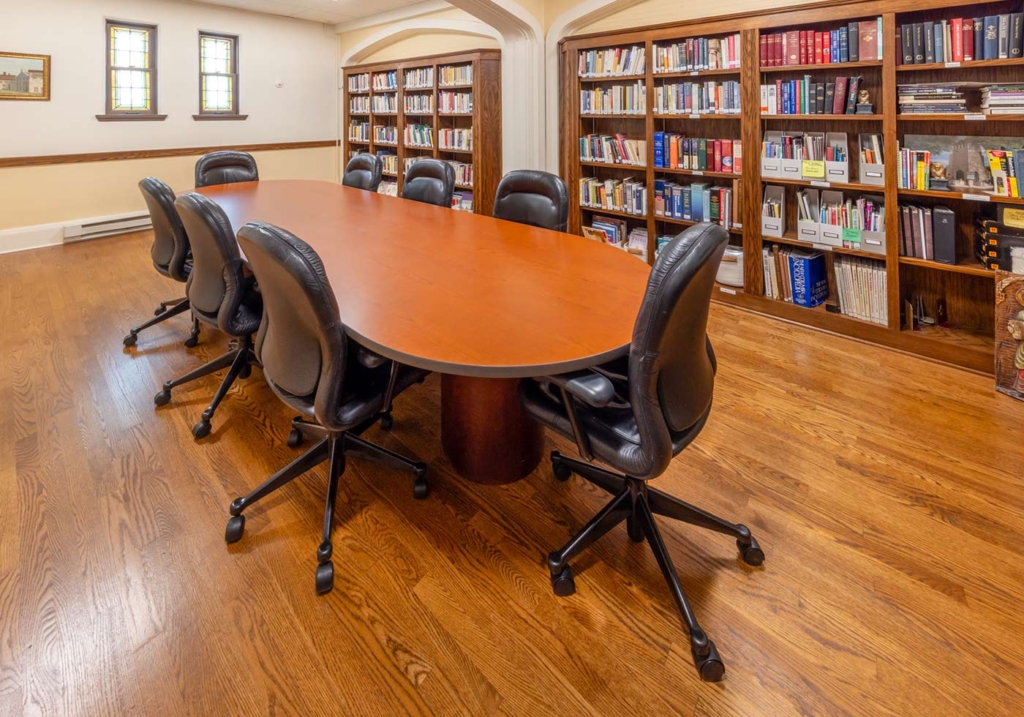 The interior of the library of first congregational UCC of Naperville. A cozy spot with a large conference table and walls of books.