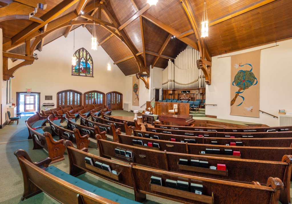 The interior of the sanctuary of first Congregational church of Naperville. Beautiful vaulted ceilings, stained glass windows, and wood church pews.